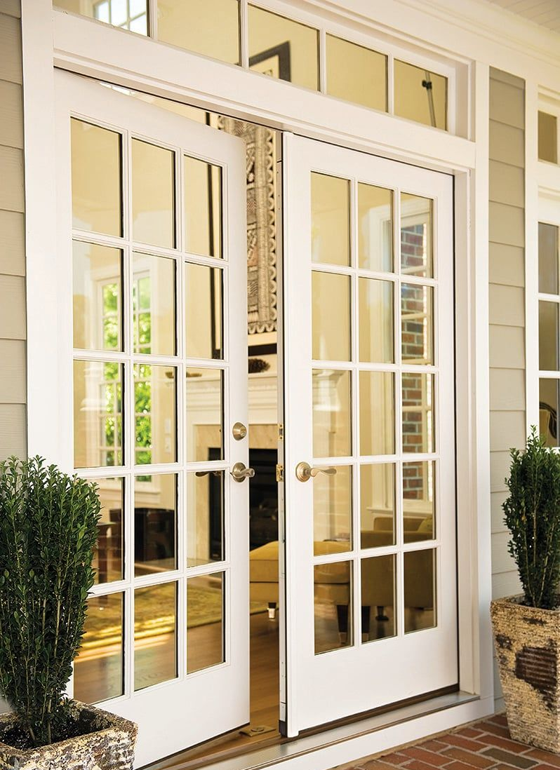 White French doors with astragal and glass panes on a beige house entrance.