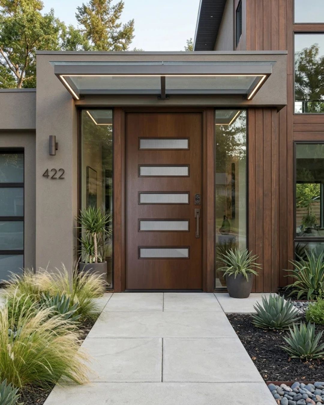 Modern house front entrance with impact fiberglass door, glass awning, and landscaped walkway
