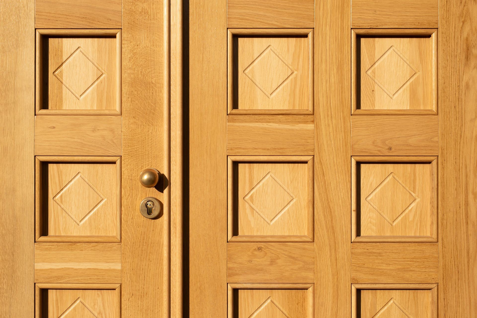 Wooden front doors with an astragal and geometric panels and brass knobs