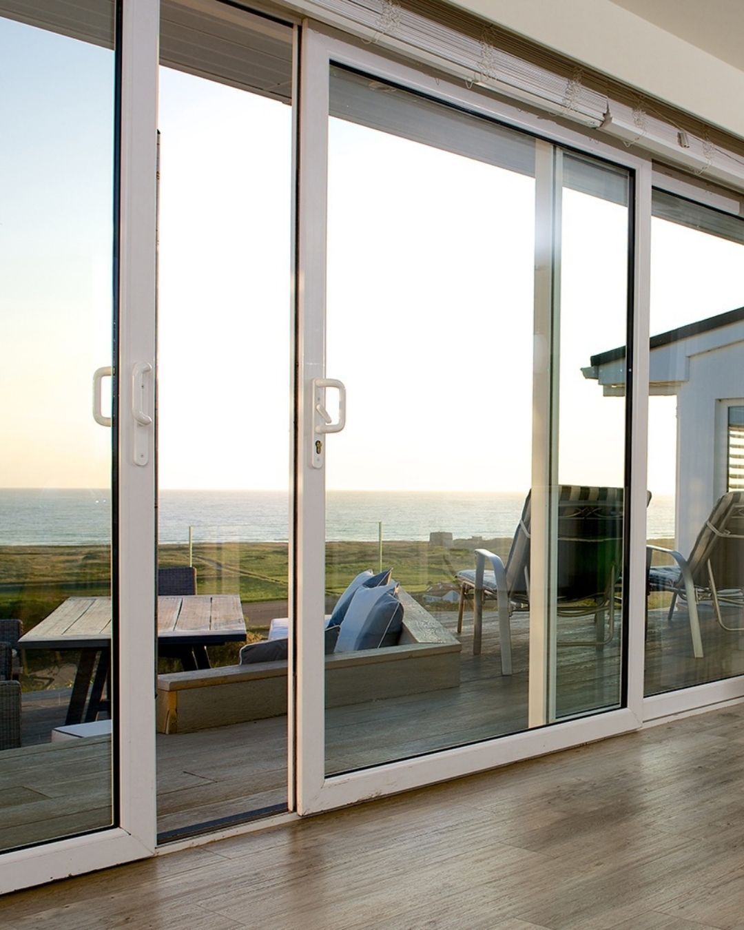 Sliding glass doors open to a pool and backyard dining area. The scene is bright with sunlight.
