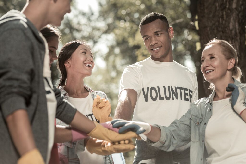 A group of volunteers are putting their hands together in a park.