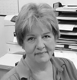 A black and white photo of a woman sitting in front of a printer.