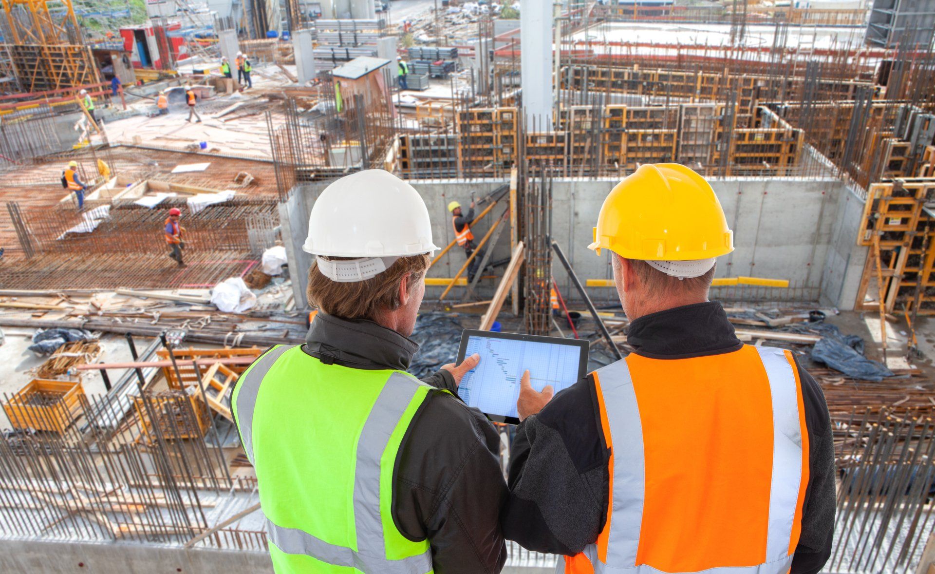 Deux ouvriers du bâtiment regardent une tablette sur un chantier de construction.