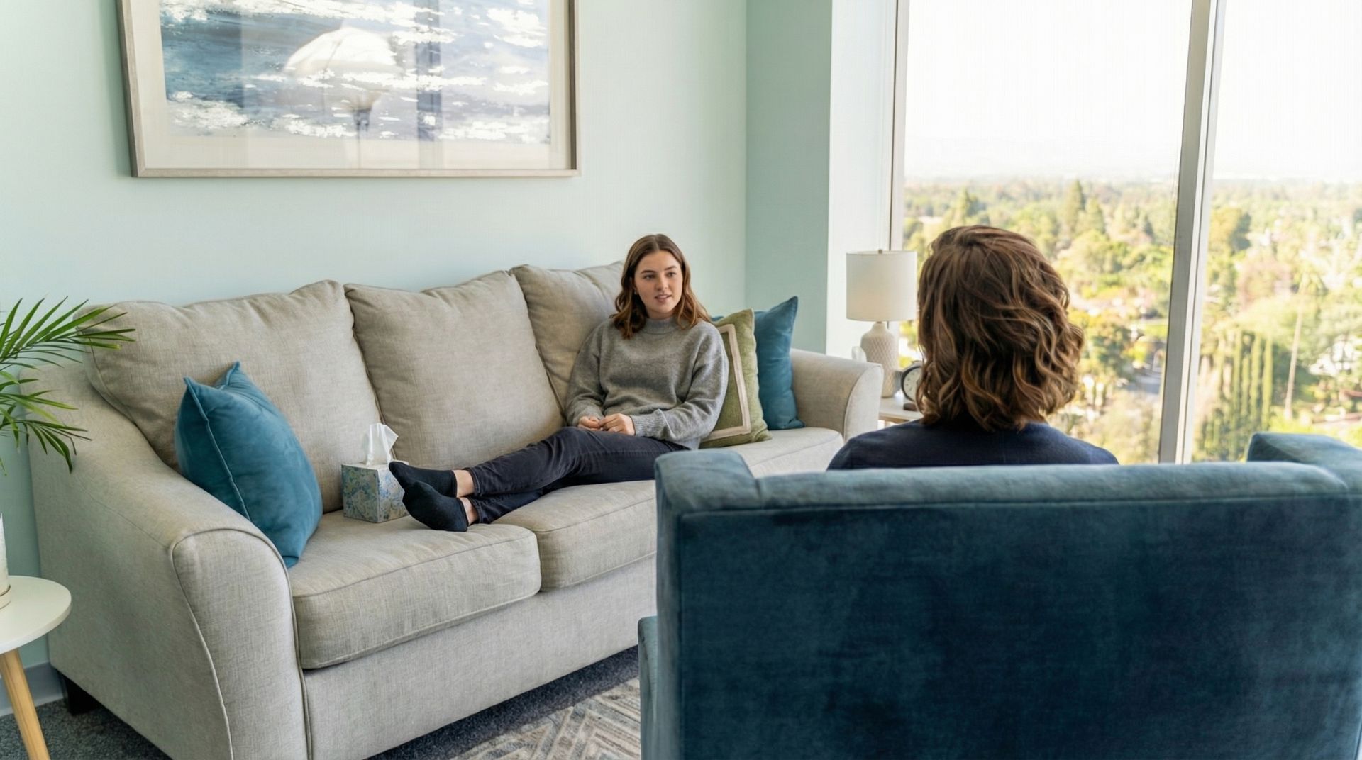 A young lady laying on the couch infront of the therapist.