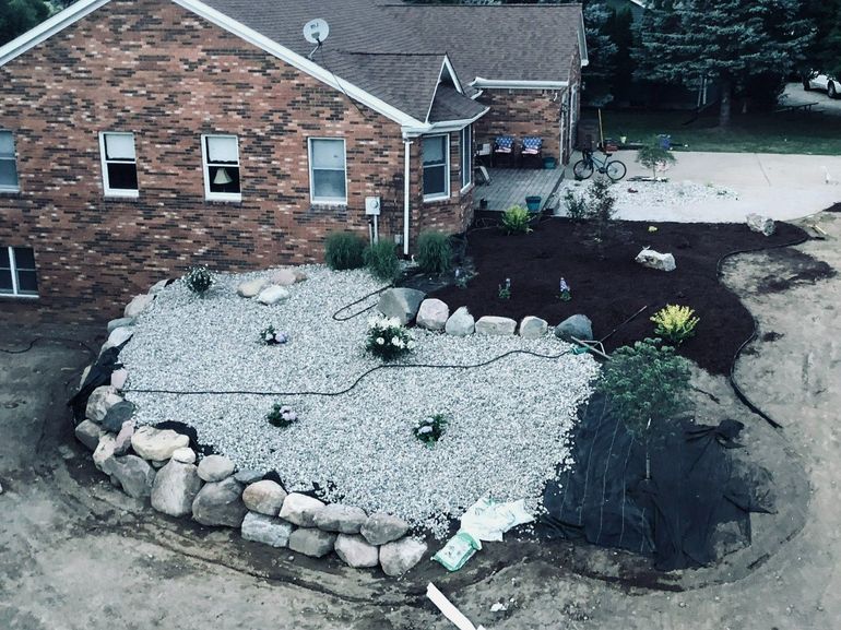 Brick house with a landscaped front yard, white gravel bed, rocks, and dark mulch.