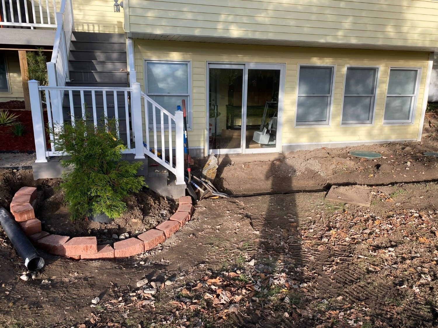 Backyard patio with white railing, sliding glass door, and small landscaped planting bed.