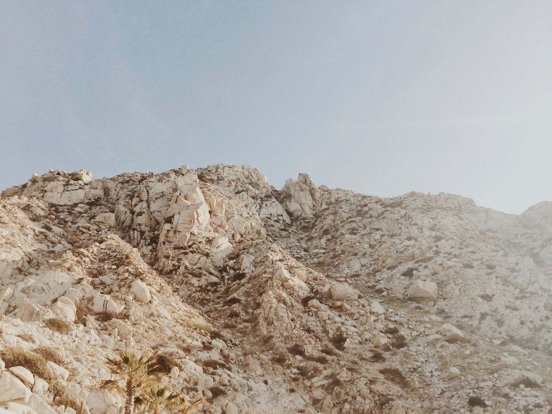 Rocky desert hillside under a pale, hazy sky