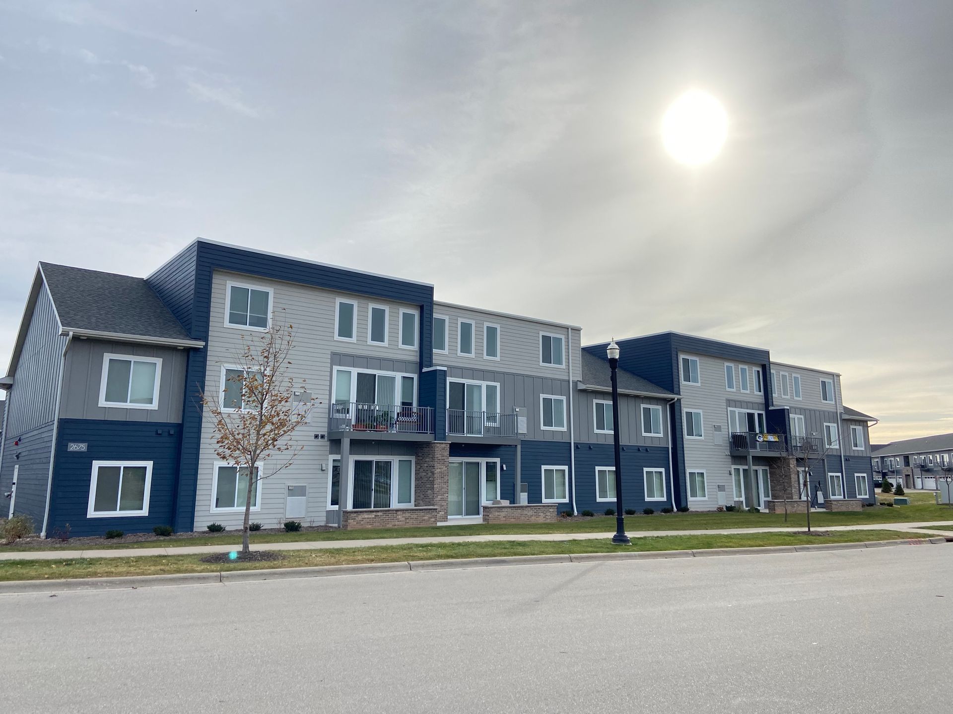 Modern apartment complex with gray and blue siding under a bright sky