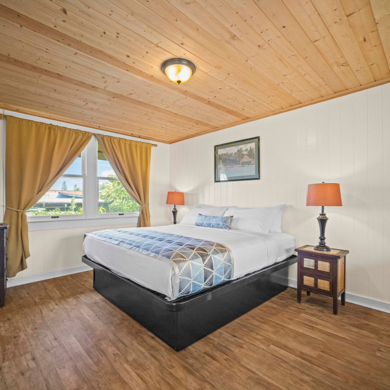 A hotel room with two beds, a wooden ceiling, and a window with yellow curtains.