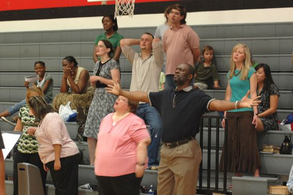 a group of adults worshipping with arms raised in a gym as a part of biblical worship in wylie tx