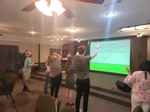5 yound adults standing at the front of the citipointe church sanctuary worshipping with arms raised