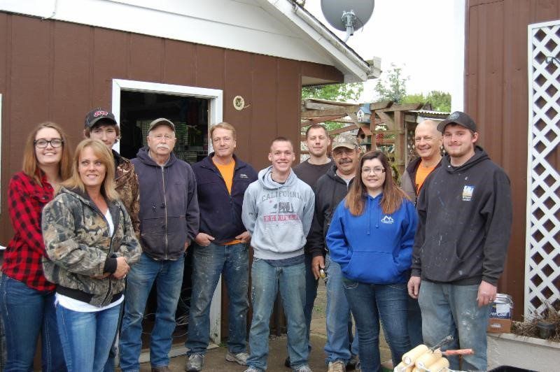 A group of people are posing for a picture in front of a brown building.