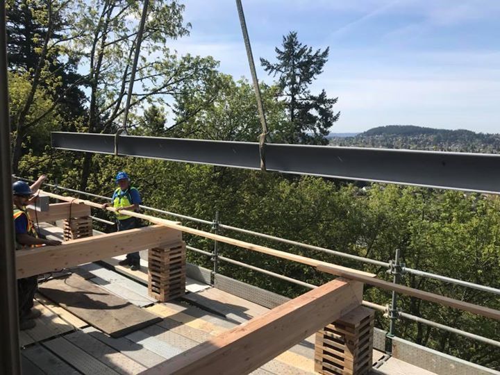 A group of construction workers are working on a balcony overlooking a forest.
