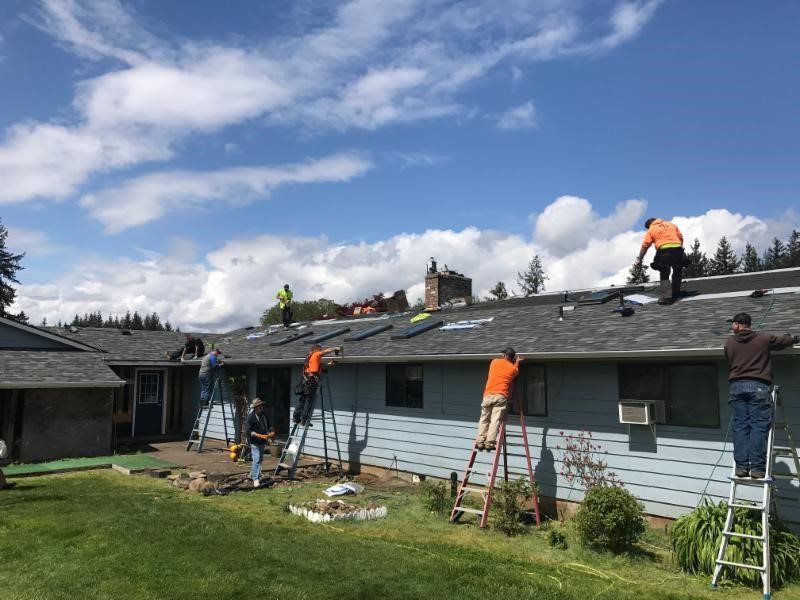 A group of men are working on the roof of a house.