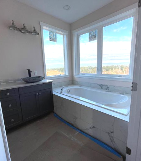 A bathroom with a tub , sink , and window.