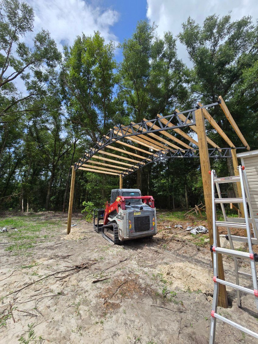 Red forklift under a wooden frame being built outdoors, with a ladder at right and trees in the background.
