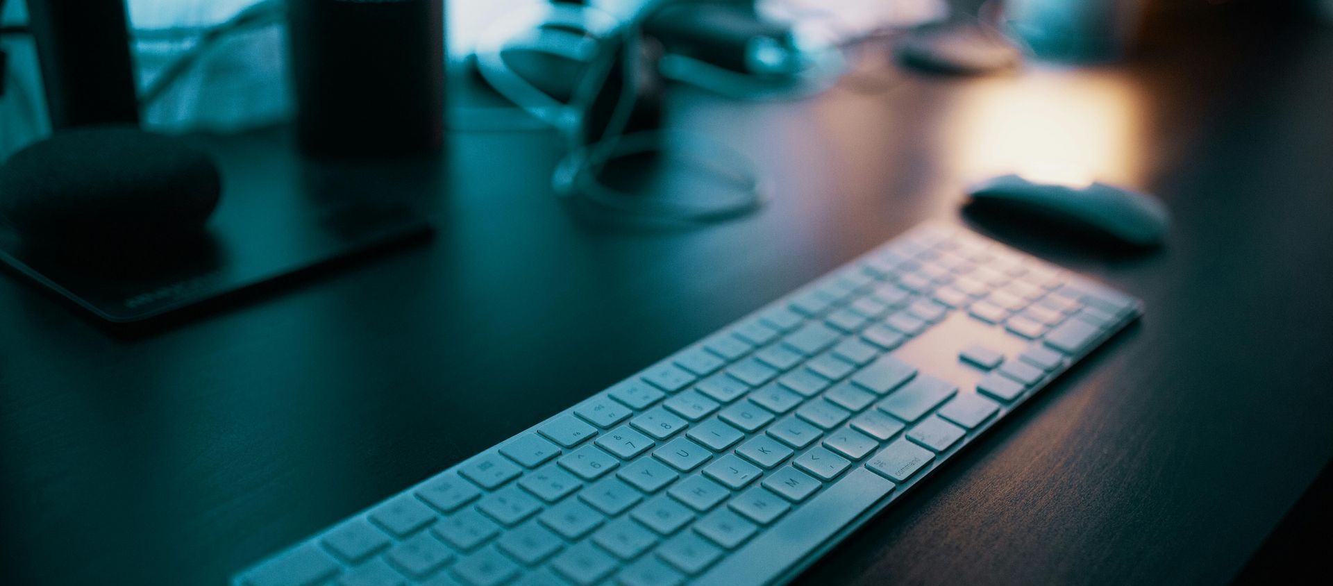 A computer , laptop , tablet and keyboard are on a wooden table.