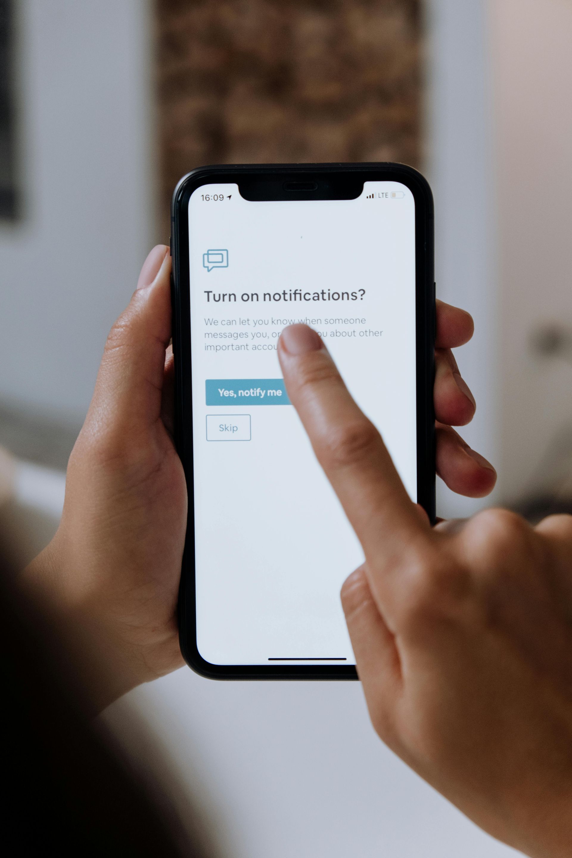 Hands holding a smartphone while a finger taps a notification settings screen