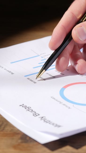 Hand holding a pen over a report with charts and graphs