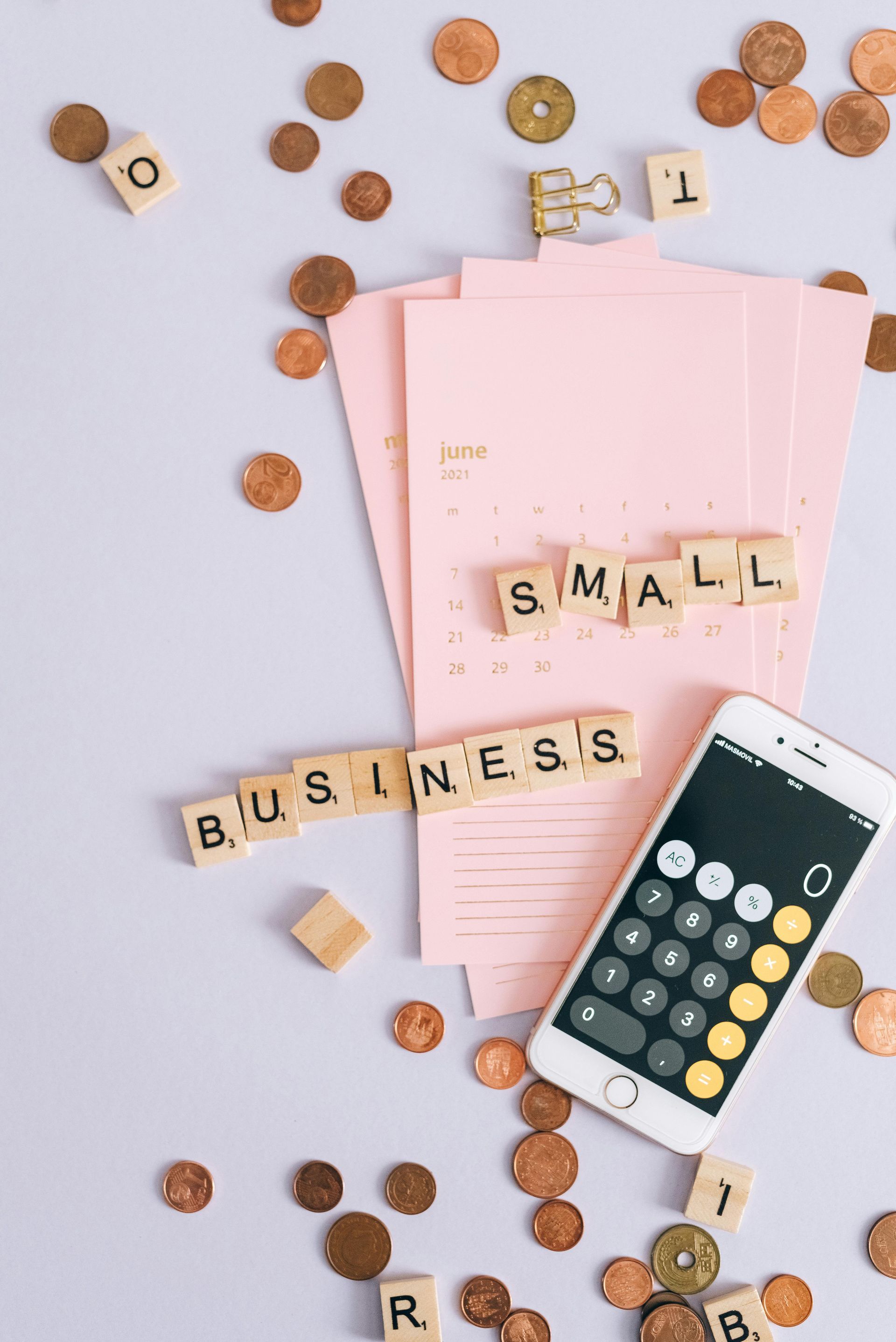 Small business accounting flat lay with pink papers, calculator, coffee, and scattered coins on a light background