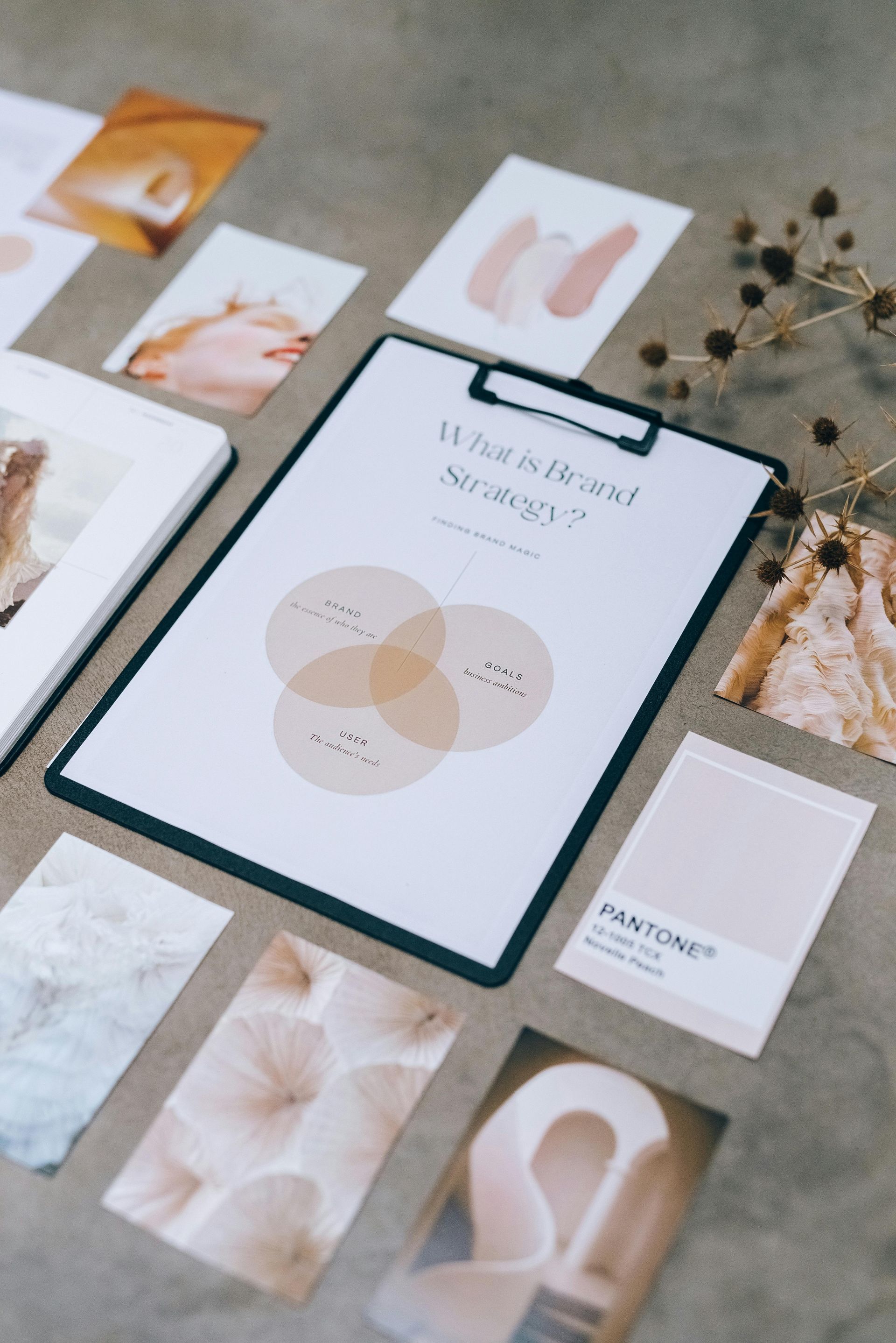 Flat lay of a beige wedding mood board with color swatches, fabric samples, and minimal stationery on a white surface