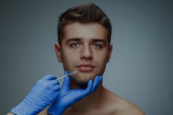 A man is getting a botox injection in his lips.