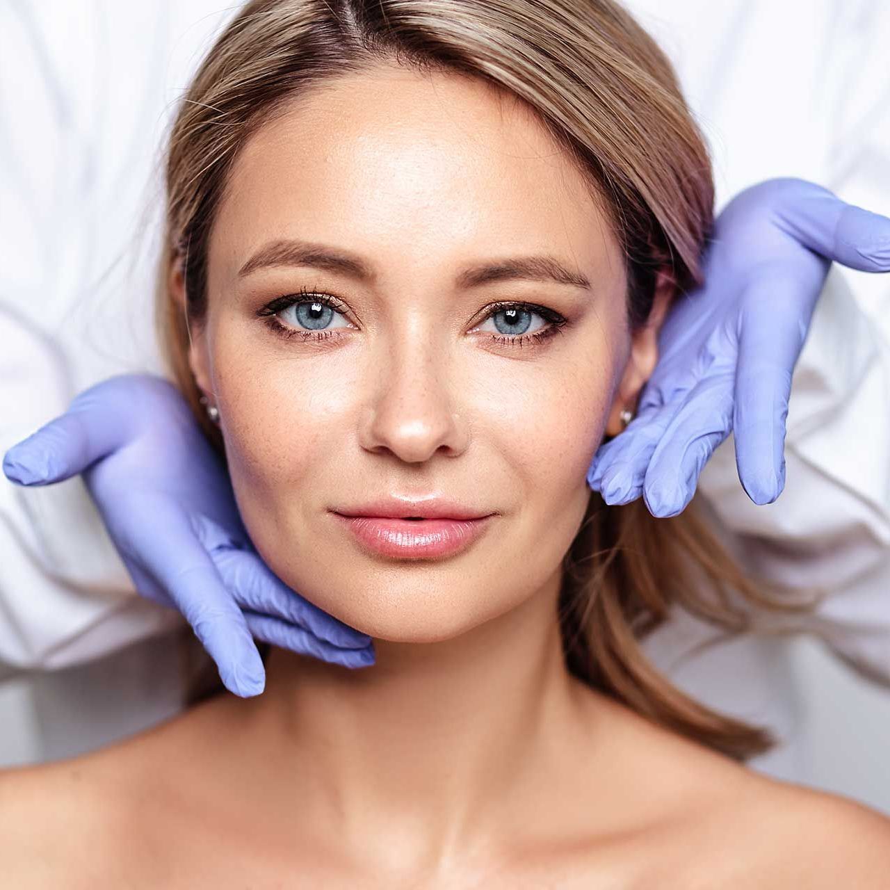 Close up portrait of young blonde woman with cosmetologyst hands in a gloves.