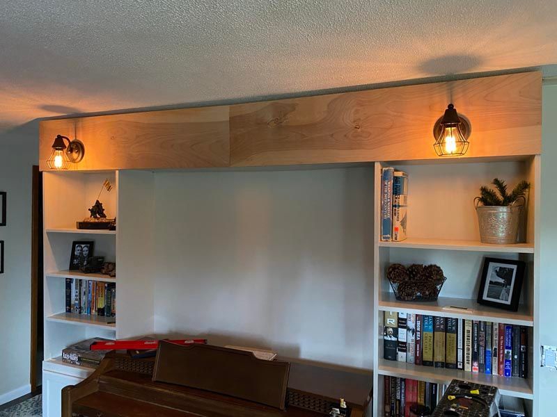 Built-in wall unit with shelves, warm lights, and a large central TV space in a living room