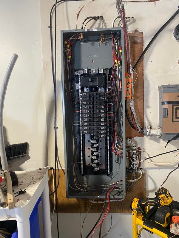 Open electrical breaker panel with wiring exposed in a wall-mounted cabinet