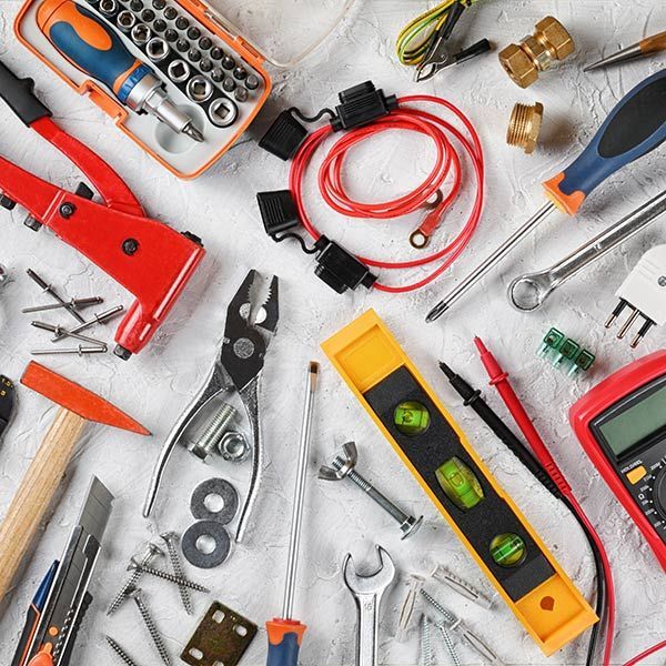 Assorted hand tools and hardware laid out on a white surface, including screwdrivers, pliers, level, and wires