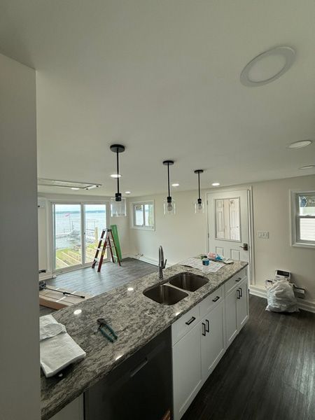 Unfinished kitchen with granite island, hanging pendant lights, and sliding glass doors to the outside.