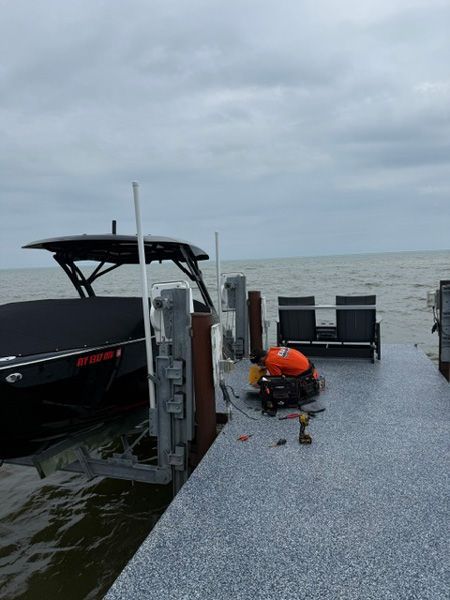 Dock by choppy water with a black boat, orange life ring, and cloudy gray sky
