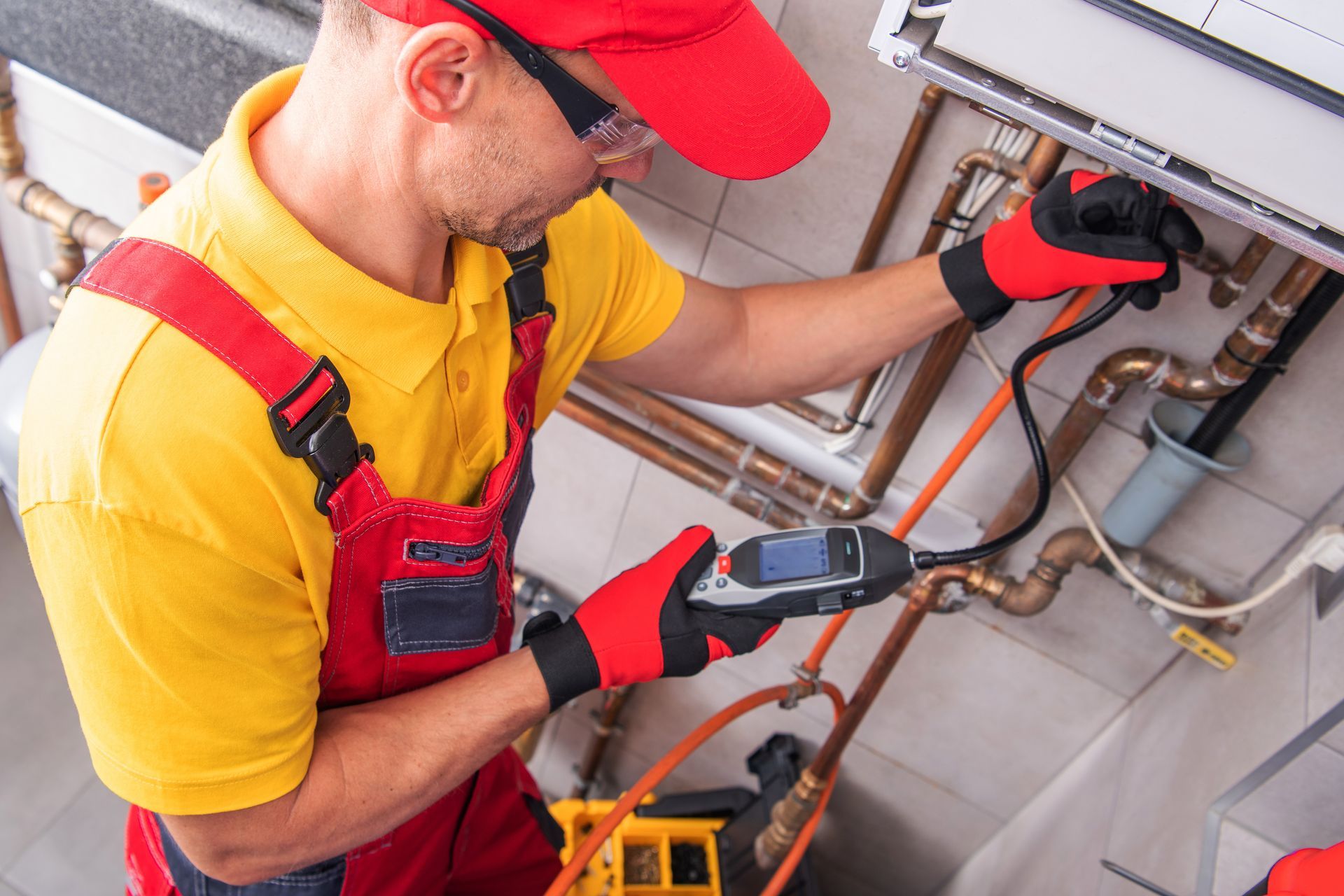 Technician using electronic detector to check gas or pipe leaks on indoor plumbing system. Technician using electronic detector to check gas or pipe leaks on indoor plumbing system.