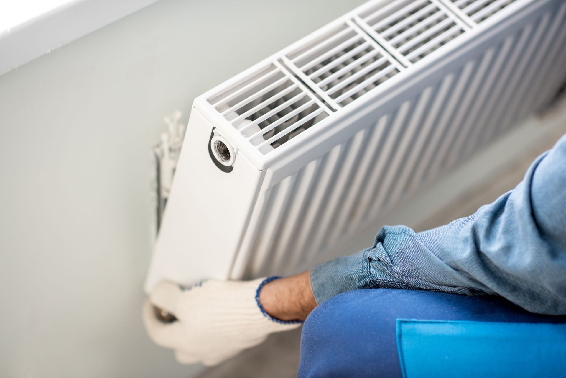 A residential heating contractor installing a wall-mounted heating unit inside a home. A residential heating contractor installing a wall-mounted heating unit inside a home.