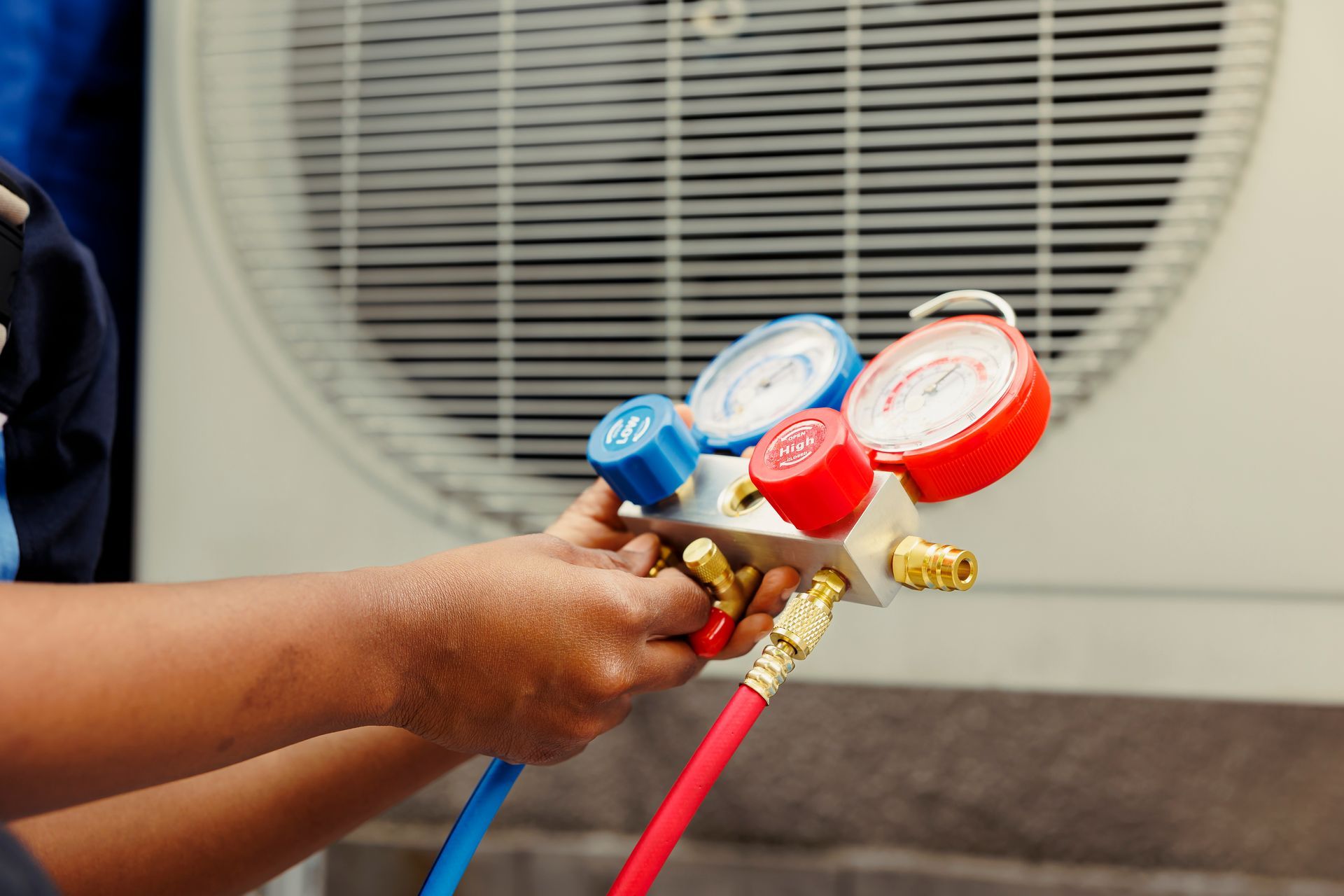 Air conditioning contractor using a manifold gauge set to check refrigerant levels on an AC unit.