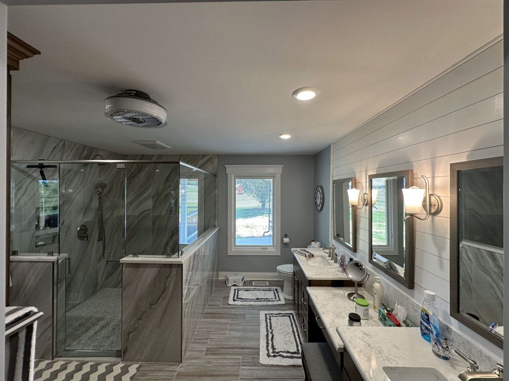A bathroom with a walk in shower , sinks , mirrors and a window.