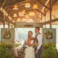 Bride and groom in a rustic barn venue, standing together and smiling during their wedding reception