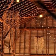 Warmly lit wooden barn interior with hanging string lights and a glowing tree-like decoration