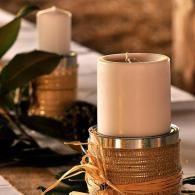 White candles in decorative gold holders on a warmly lit table.