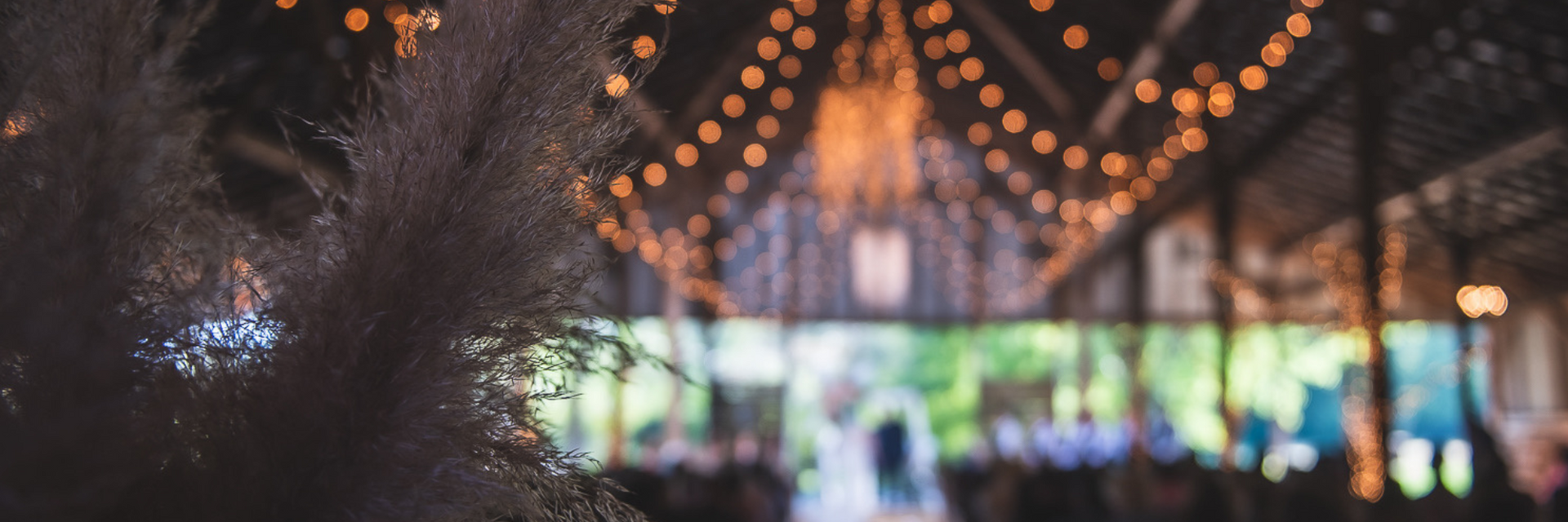 String lights hanging over an outdoor crowd with a brightly lit stage in the distance