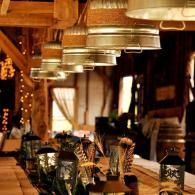 Warmly lit restaurant table with glassware and hanging metal lamps in a rustic interior