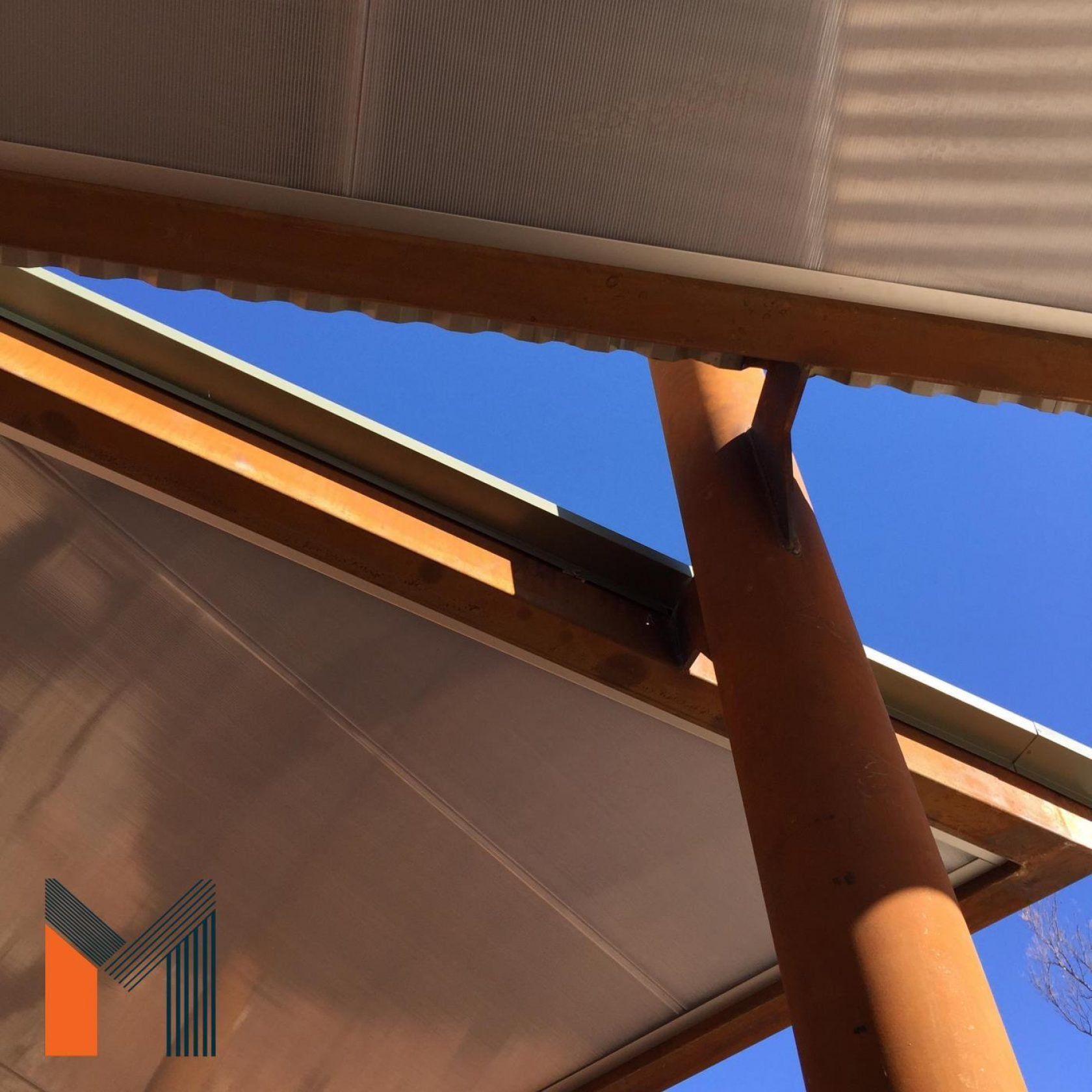 Wooden shelter with clear roof against a blue sky.