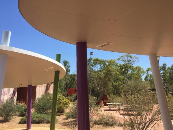 Colorful, modern park shelter with circular roofs and purple, green, and white support columns.