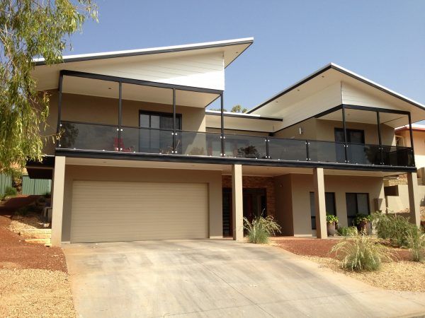 Two-story house with beige facade, balconies, and a driveway.