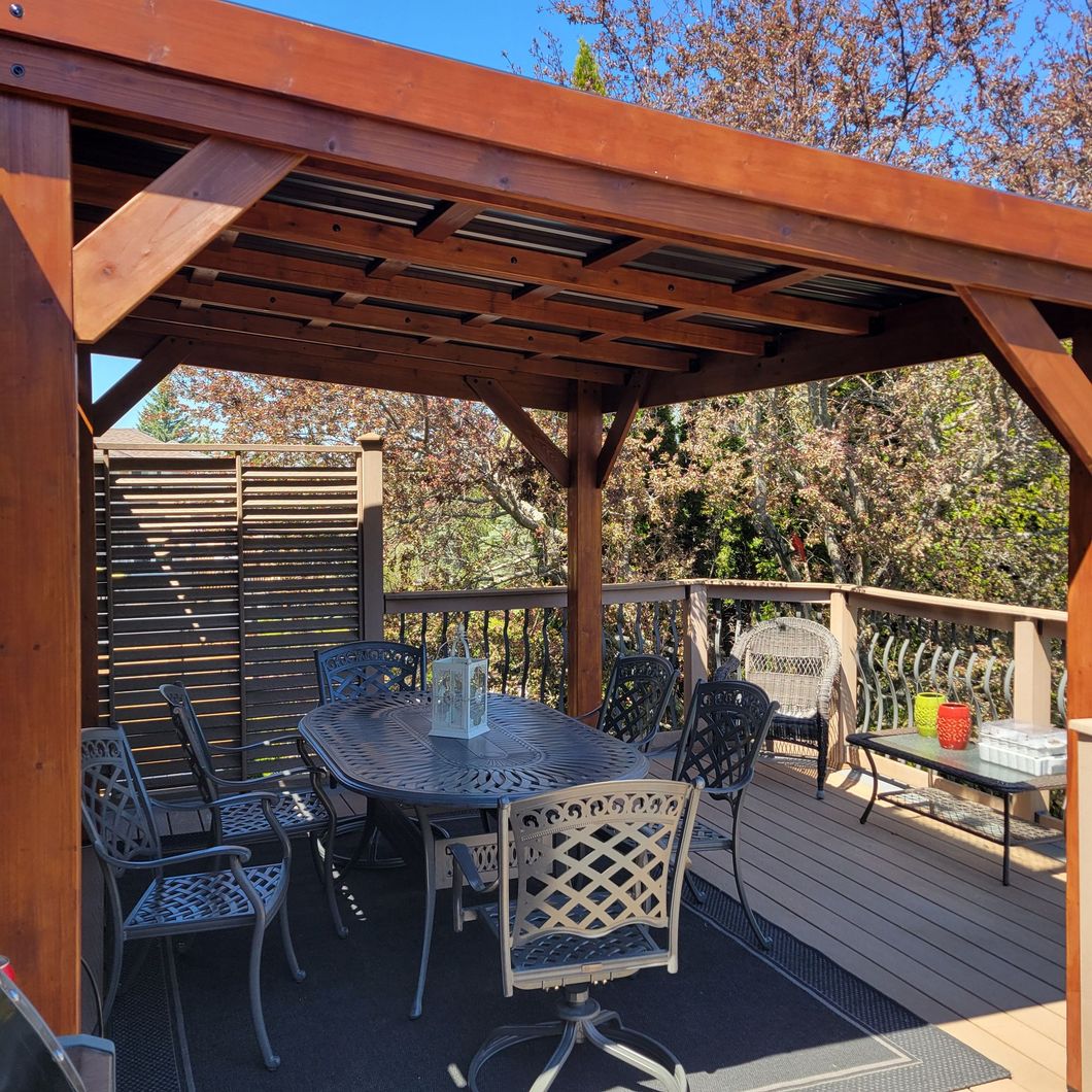 Patio with a wooden pergola, dining set, and privacy screen.