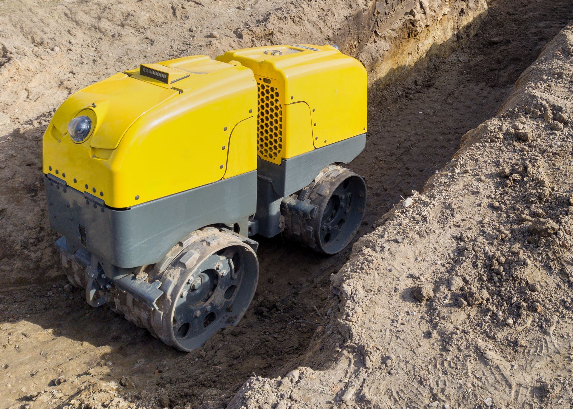 Small yellow-and-gray tracked robot on a dirt slope outdoors