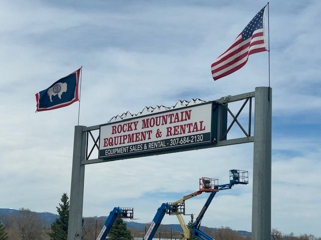 Rocky Mountain Equipment & Rental sign with U.S. and Wyoming flags and cherry picker lifts below