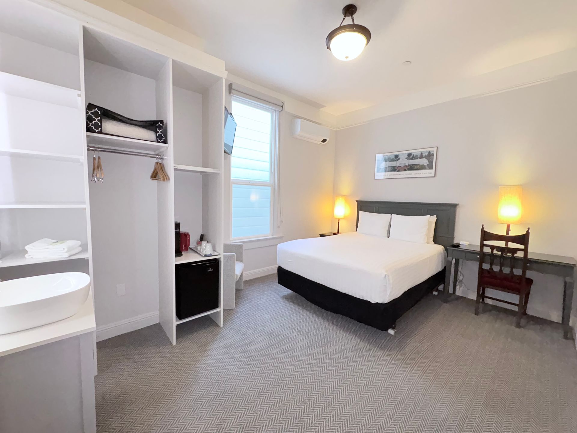 A hotel room with a bed , desk , chair and closet.
