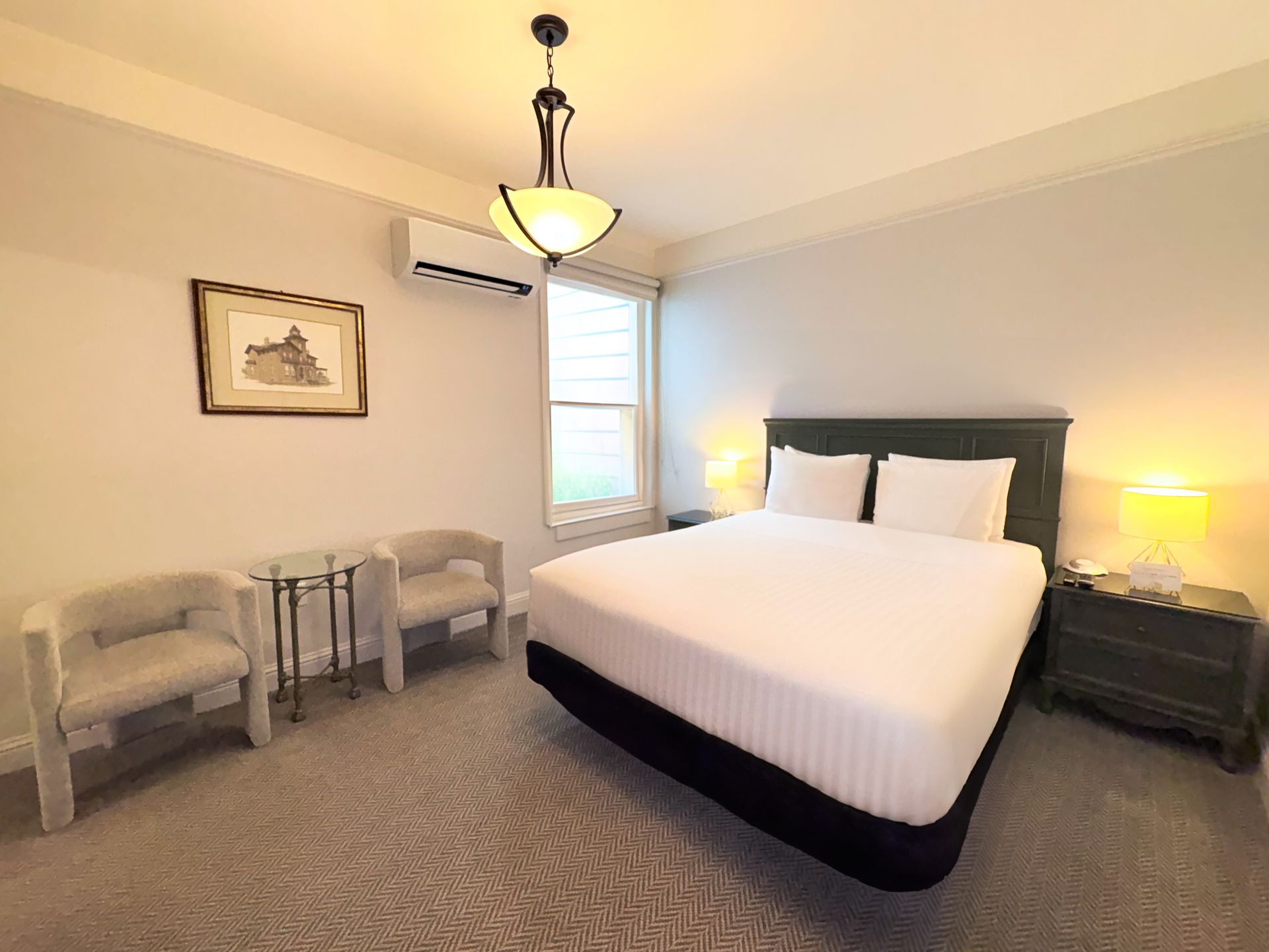 A hotel room with a bed , chairs and a table