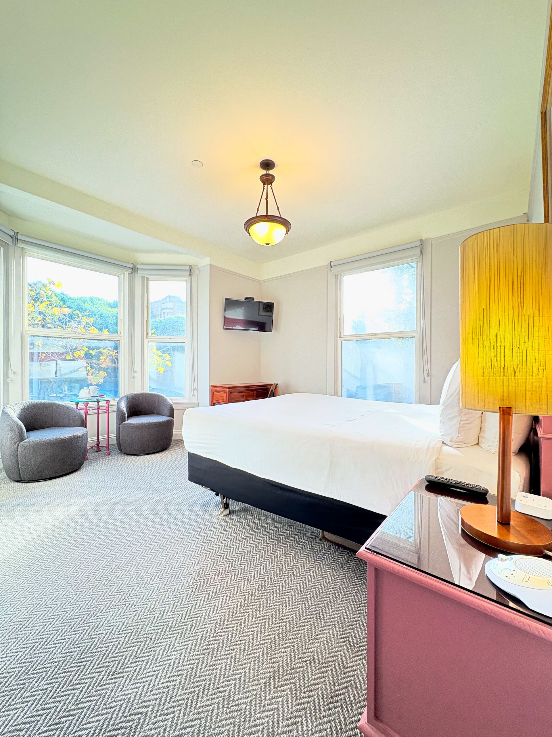 A hotel room with a king size bed , chairs and a lamp.